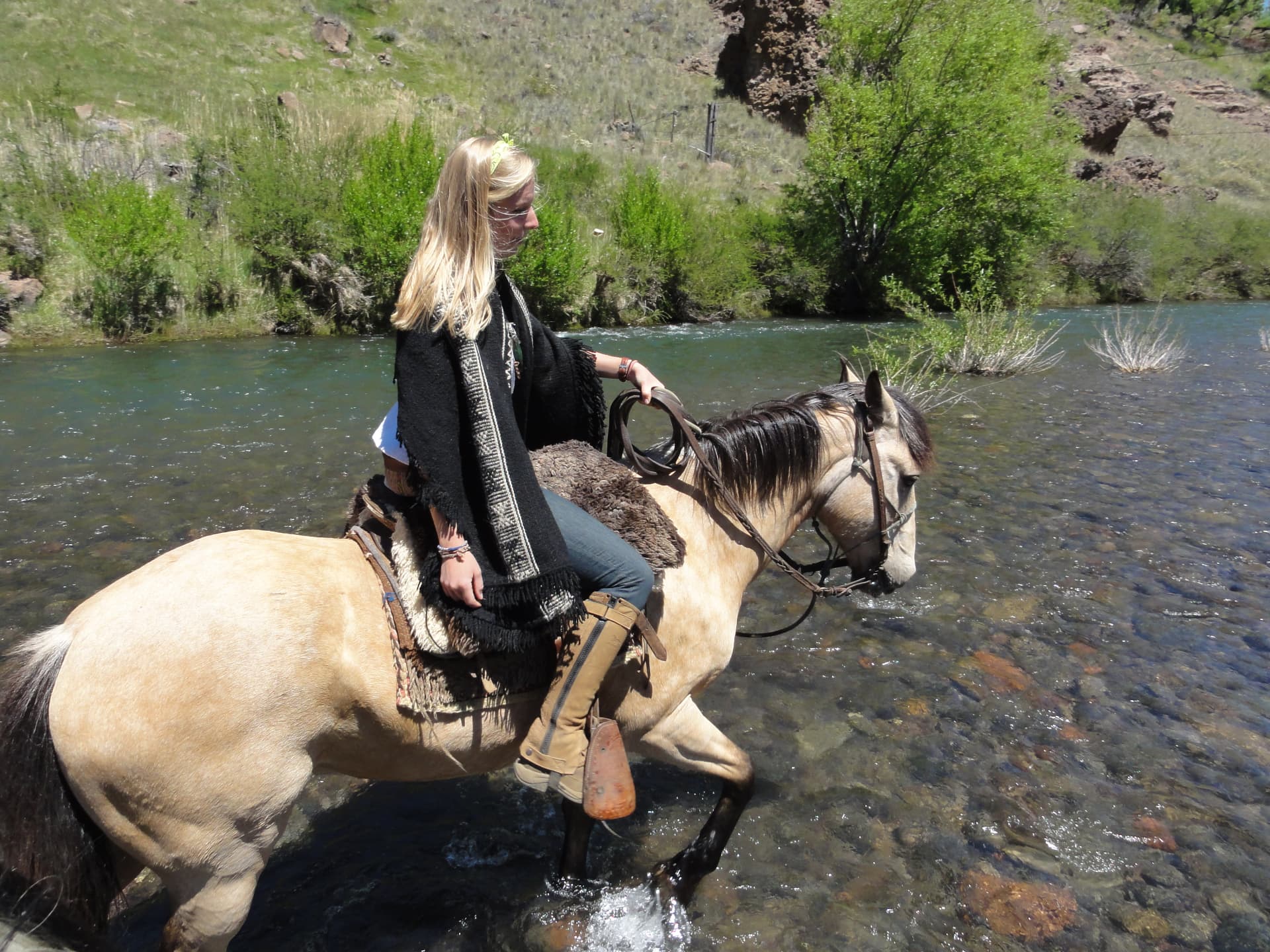 Caroline Bulstra riding a horse through a river in Argentina